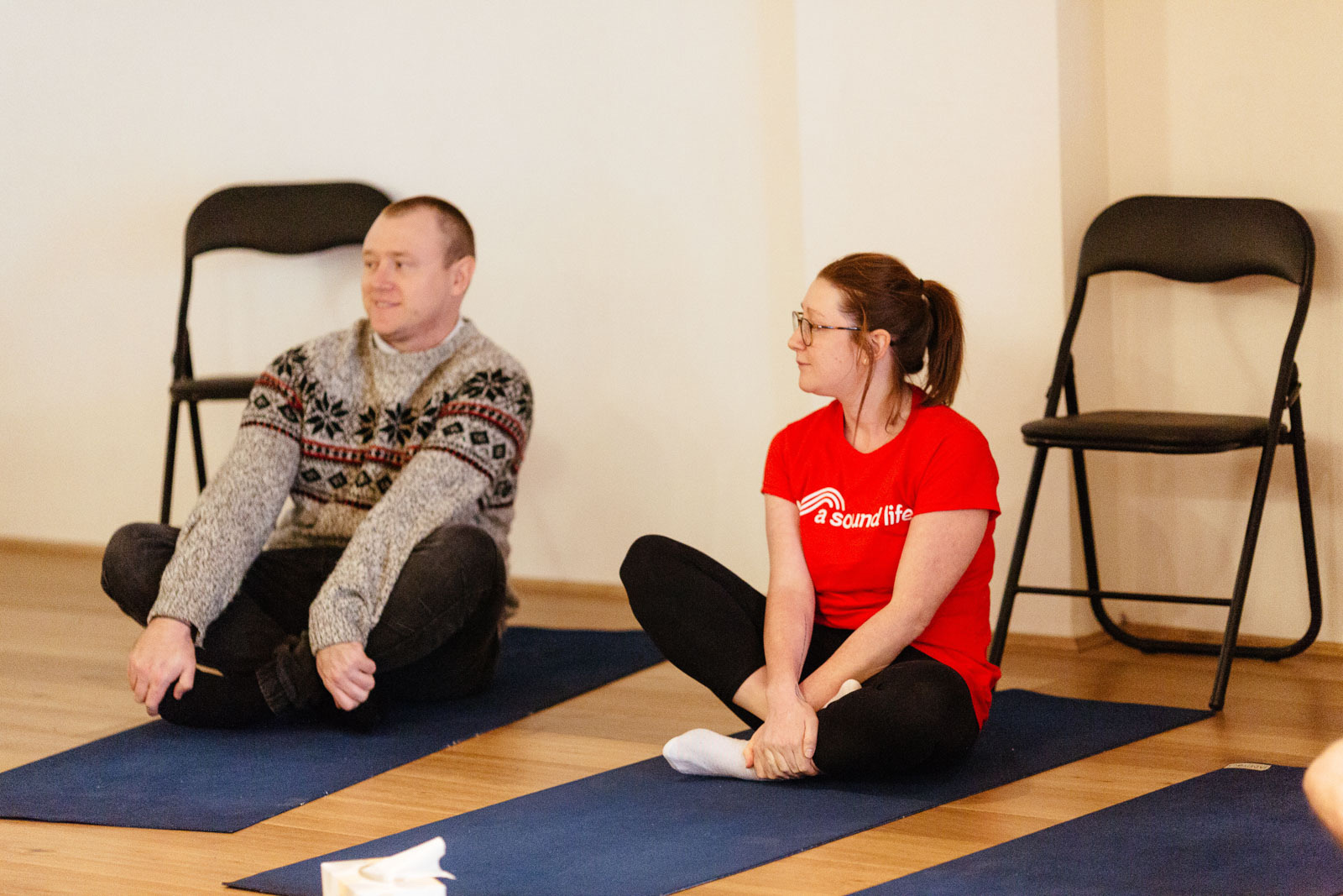 An A Sound Life teacher sitting cross-legged on a mat, attentively watching the room